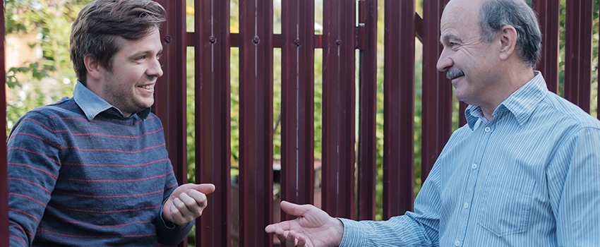 two neighbours talking next to fence