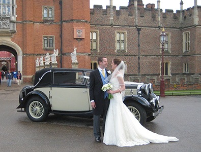 couple posing in front of wedding car