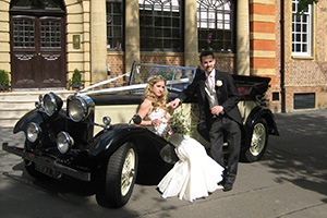 couple posing in vintage wedding cars