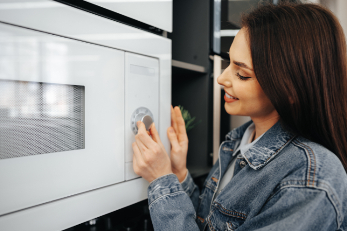A woman using a microwave - What Is Office Kitchen Etiquette