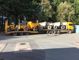 A number of dumpers loaded onto a truck's trailer