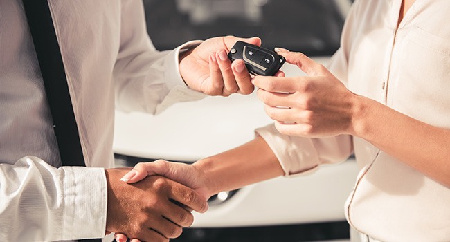 man and lady shaking hands over a car purchase