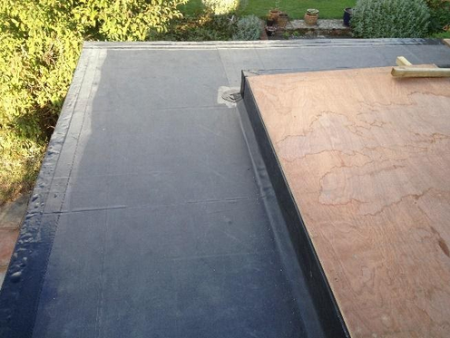 Single ply flat roof with a raised edge beside a tiled roof